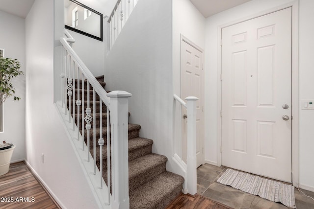 foyer entrance with stairway, wood finished floors, and baseboards