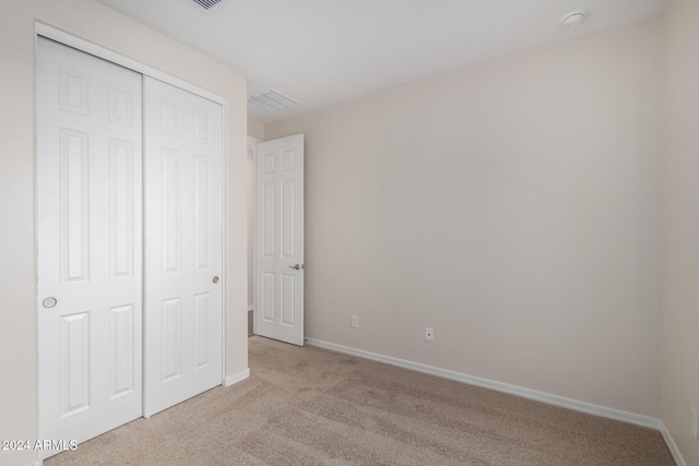 unfurnished bedroom featuring light carpet and a closet