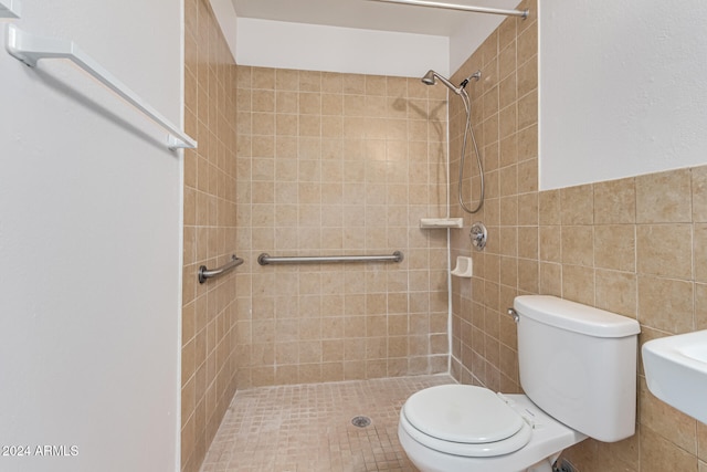 bathroom with a tile shower, toilet, and tile walls