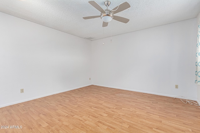 empty room with ceiling fan, light hardwood / wood-style flooring, and a textured ceiling