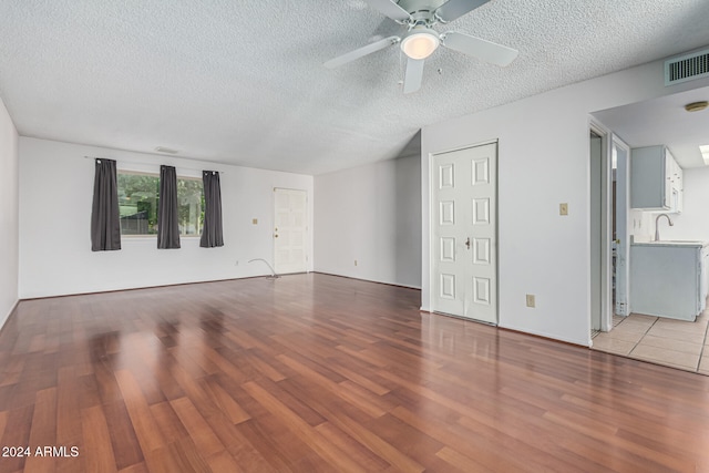 spare room with ceiling fan, light hardwood / wood-style floors, and a textured ceiling