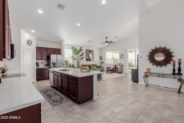 kitchen featuring ceiling fan, sink, lofted ceiling, a kitchen island with sink, and appliances with stainless steel finishes
