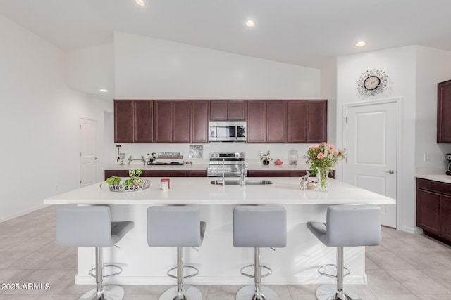 kitchen with a breakfast bar, a center island with sink, high vaulted ceiling, and stainless steel appliances
