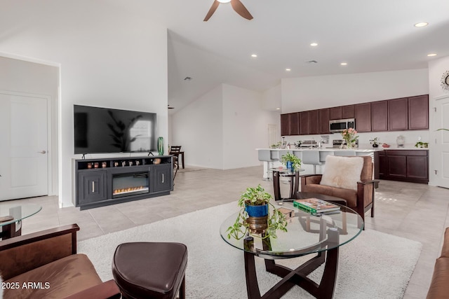 living room with ceiling fan, high vaulted ceiling, and light tile patterned floors