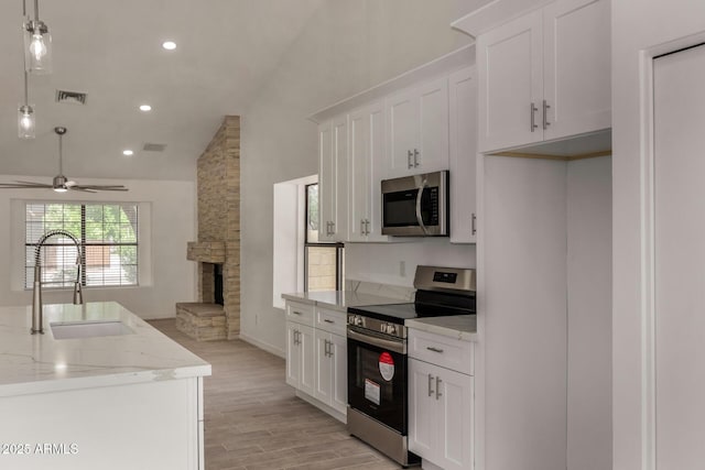 723 E Piute Ave, Phoenix, AZ 85024 - kitchen featuring stainless steel appliances, a ceiling fan, a fireplace, light wood-style floors, and white cabinets