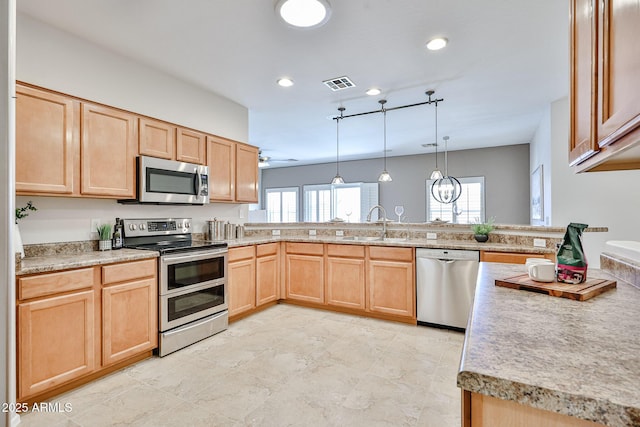 kitchen featuring light brown cabinetry, a peninsula, appliances with stainless steel finishes, and visible vents