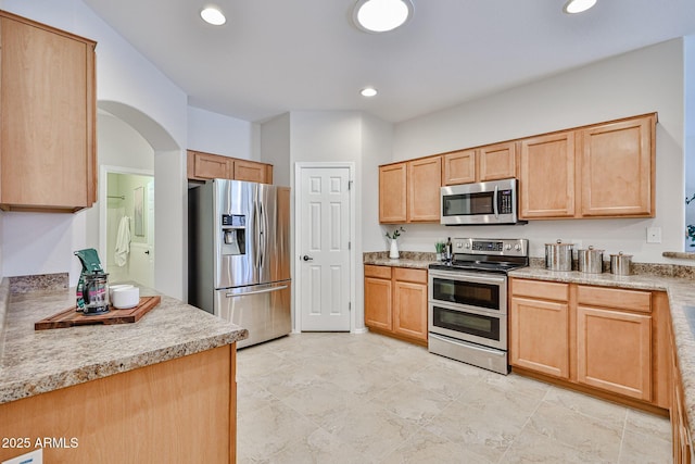 kitchen with arched walkways, light brown cabinetry, light countertops, stainless steel appliances, and recessed lighting
