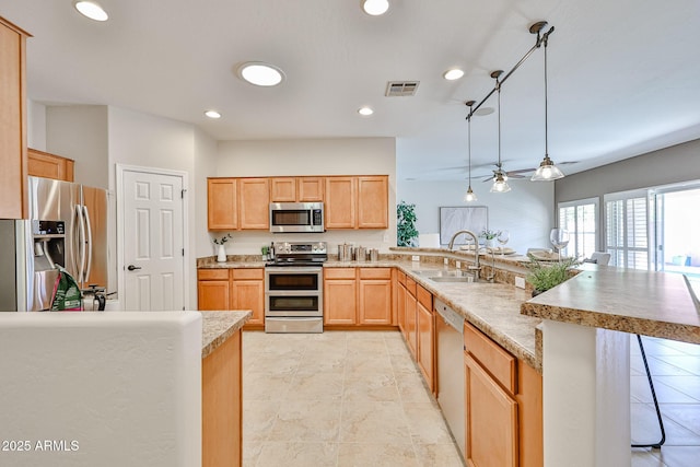 kitchen featuring appliances with stainless steel finishes, a sink, light brown cabinets, a peninsula, and visible vents