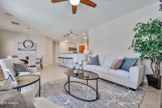 living area with baseboards, visible vents, light tile patterned floors, and ceiling fan with notable chandelier