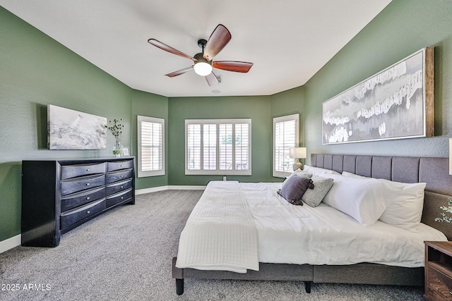 carpeted bedroom featuring baseboards, multiple windows, and ceiling fan