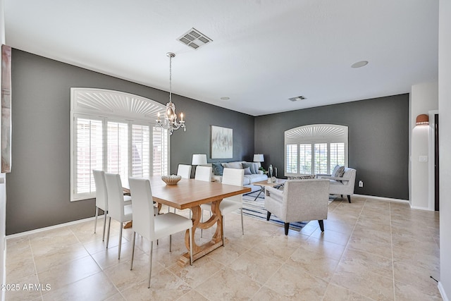 dining area with visible vents, baseboards, an accent wall, and a notable chandelier