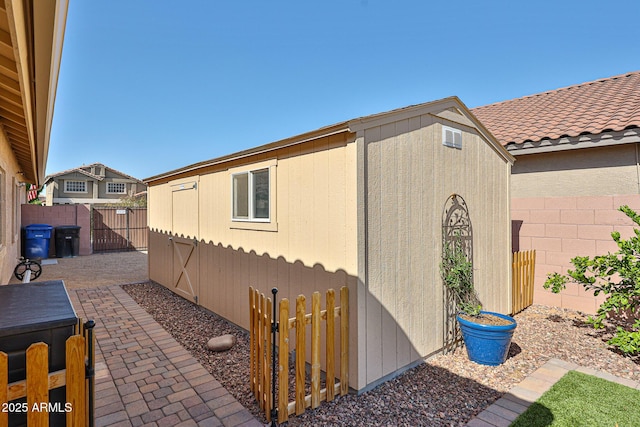 view of property exterior with an outdoor structure, a tiled roof, and a fenced backyard