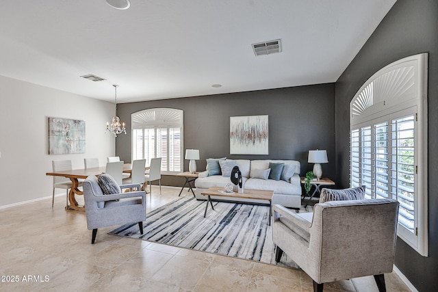 living room featuring visible vents, baseboards, a healthy amount of sunlight, and an inviting chandelier