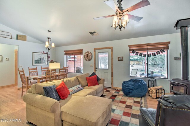3047 Ponderosa Rd, Overgaard, AZ 85933 - living area with vaulted ceiling, a wood stove, ceiling fan with notable chandelier, visible vents, and wood finished floors