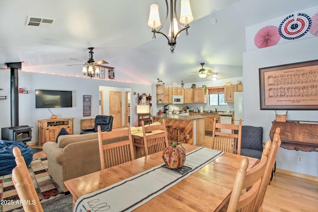 3047 Ponderosa Rd, Overgaard, AZ 85933 - dining space with vaulted ceiling, ceiling fan, visible vents, and a wood stove