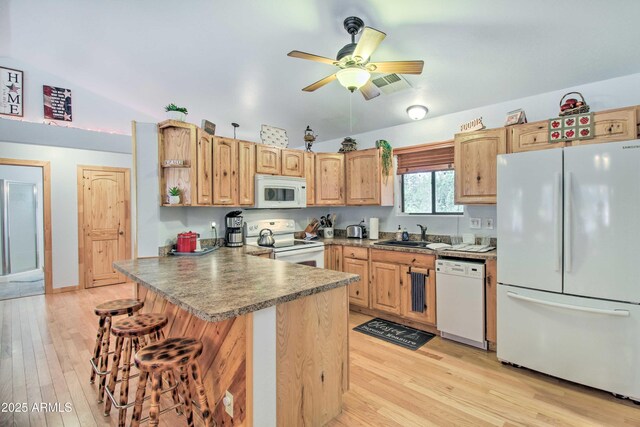 3047 Ponderosa Rd, Overgaard, AZ 85933 - kitchen with a breakfast bar area, light wood-style floors, a peninsula, and white appliances