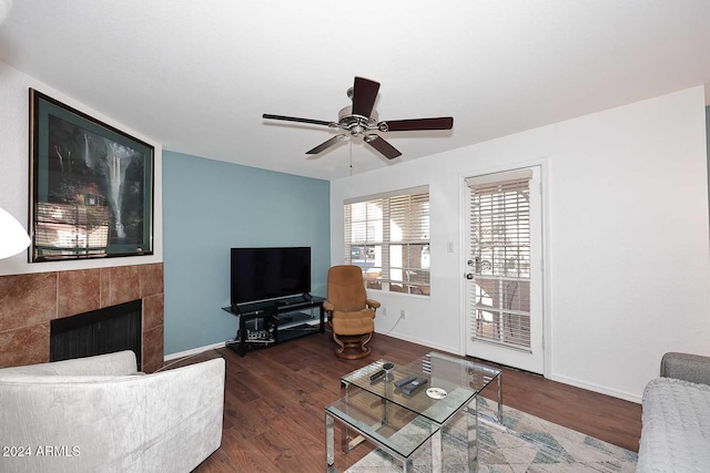 living room with ceiling fan, a fireplace, and dark wood-type flooring