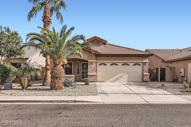 view of front of house featuring fence, a tile roof, concrete driveway, stucco siding, and a garage