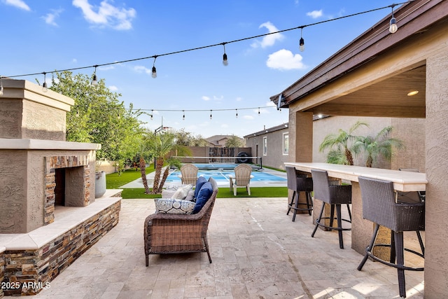 view of patio / terrace with fence, exterior fireplace, a fenced in pool, and outdoor dry bar