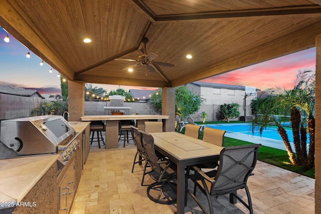 view of patio / terrace with grilling area, an outdoor kitchen, a fenced backyard, and outdoor dry bar