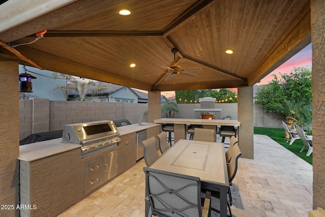 view of patio featuring exterior kitchen, area for grilling, outdoor dining area, and a fenced backyard