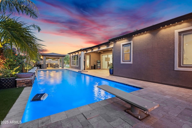 outdoor pool featuring a gazebo, a jacuzzi, a patio area, and a diving board