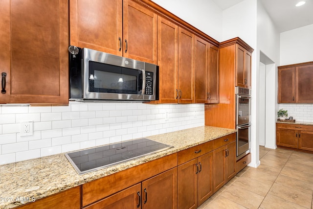 kitchen featuring light stone counters, backsplash, appliances with stainless steel finishes, and brown cabinets