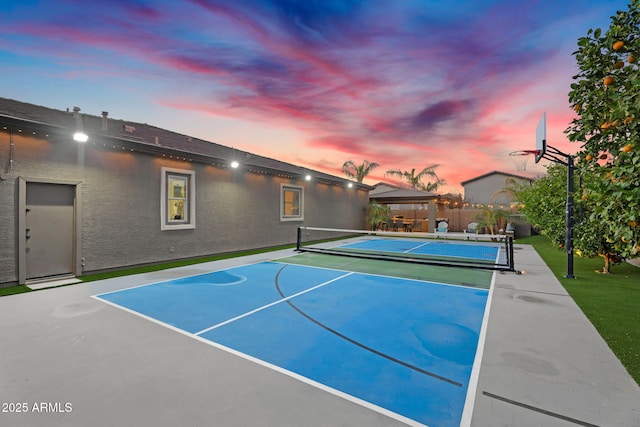 view of tennis court featuring basketball hoop and fence