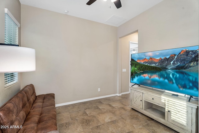 living room featuring a ceiling fan, stone finish floor, visible vents, and baseboards