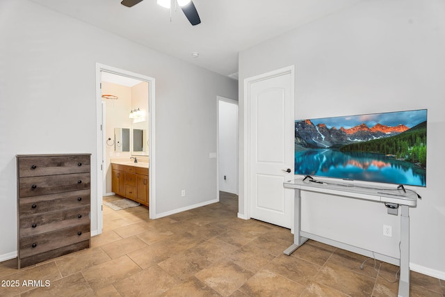 bedroom with connected bathroom, stone finish flooring, ceiling fan, baseboards, and a sink