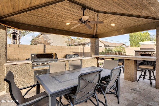 view of patio / terrace with grilling area, fence, outdoor wet bar, outdoor dining area, and area for grilling