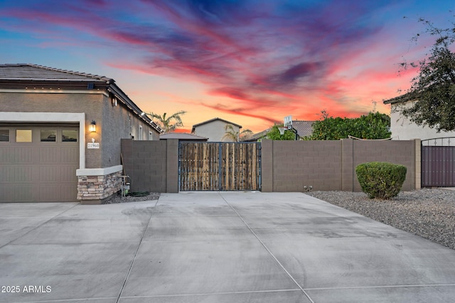 view of side of property featuring stucco siding, stone siding, fence, and a gate