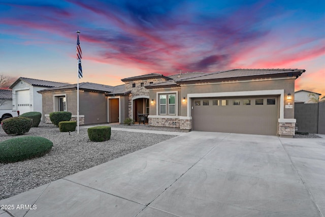 prairie-style home featuring a garage, stone siding, driveway, and stucco siding