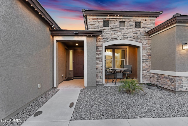 view of exterior entry with stone siding and stucco siding