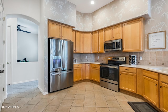 kitchen featuring appliances with stainless steel finishes, sink, backsplash, ceiling fan, and light tile patterned floors