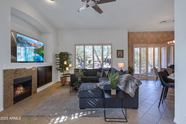 tiled living room with ceiling fan and a fireplace