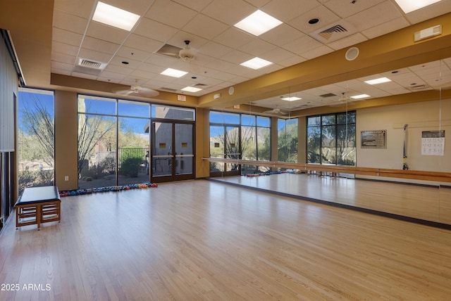 workout room with light hardwood / wood-style floors, a paneled ceiling, and ceiling fan