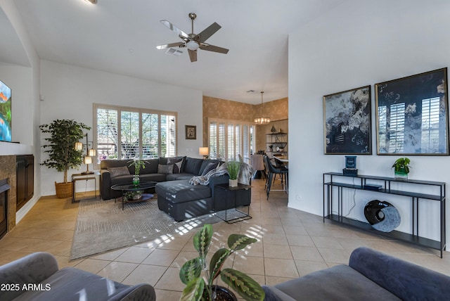 tiled living room featuring ceiling fan with notable chandelier