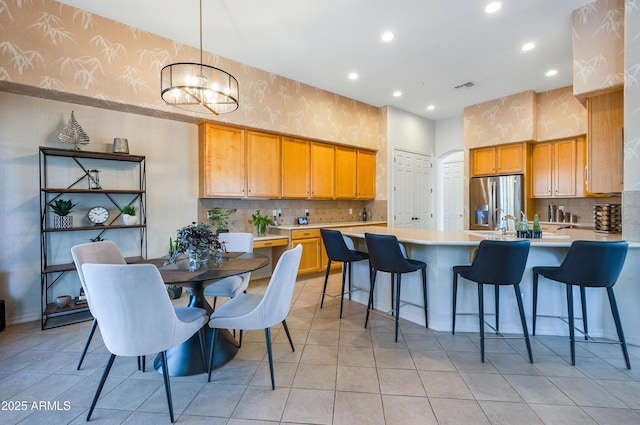 kitchen with decorative light fixtures, backsplash, stainless steel fridge with ice dispenser, a notable chandelier, and light tile patterned floors