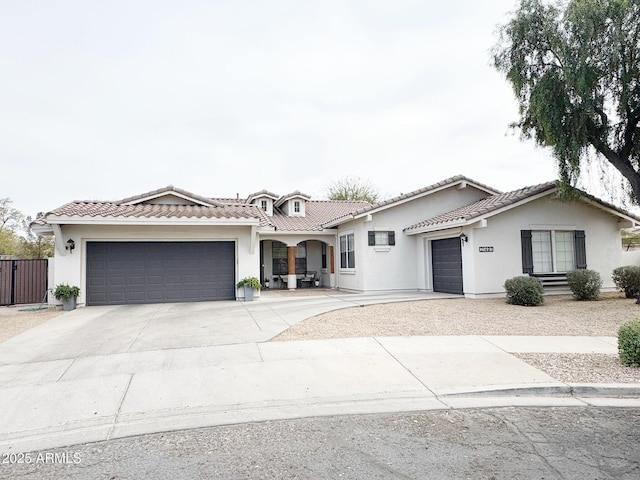 view of front of house with a garage, driveway, a tile roof, and stucco siding