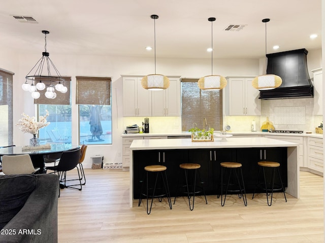 kitchen featuring visible vents, stainless steel gas stovetop, custom exhaust hood, and light countertops