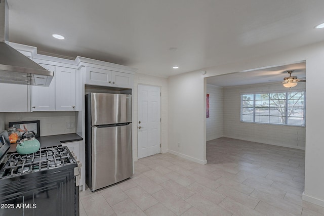 kitchen featuring wall chimney exhaust hood, white cabinetry, appliances with stainless steel finishes, ceiling fan, and decorative backsplash