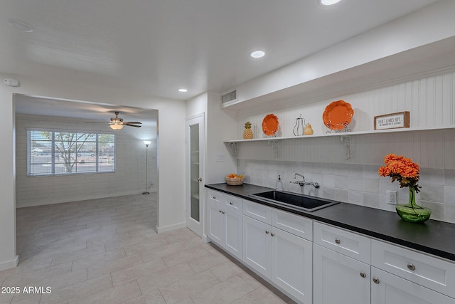 kitchen featuring white cabinetry, sink, backsplash, and ceiling fan