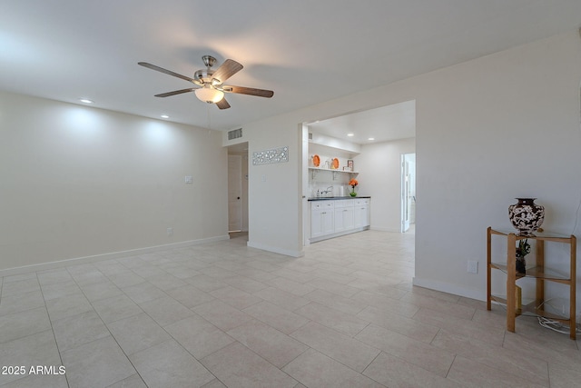 unfurnished living room featuring sink, light tile patterned floors, and ceiling fan