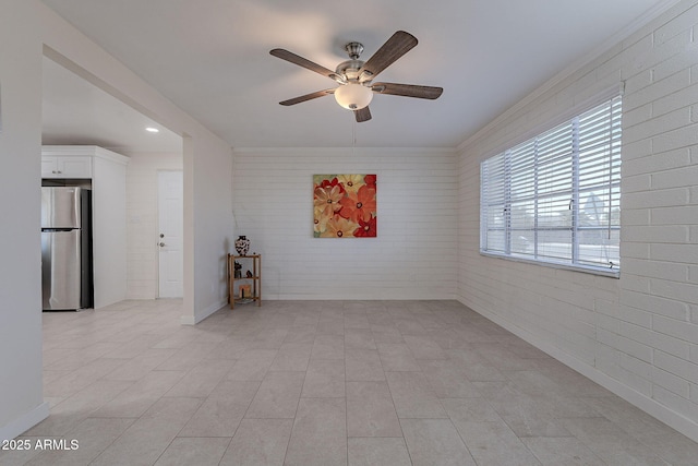 empty room featuring light tile patterned floors, ceiling fan, and brick wall