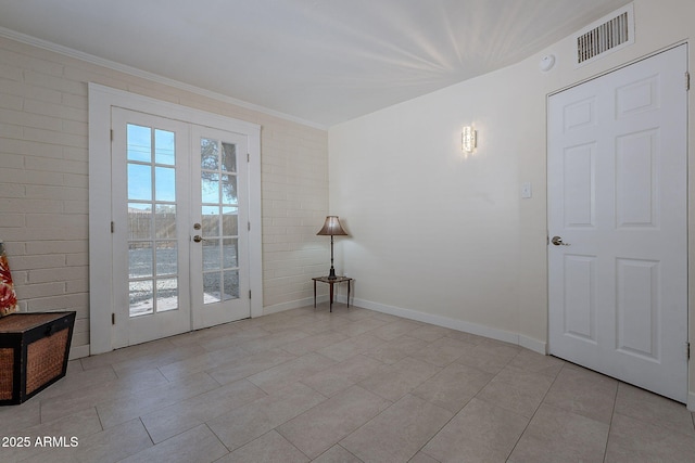 entryway featuring light tile patterned flooring, brick wall, a healthy amount of sunlight, and french doors