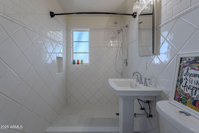 bathroom with a tile shower, tile walls, and toilet