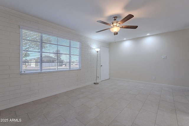 tiled empty room with ornamental molding, brick wall, and ceiling fan