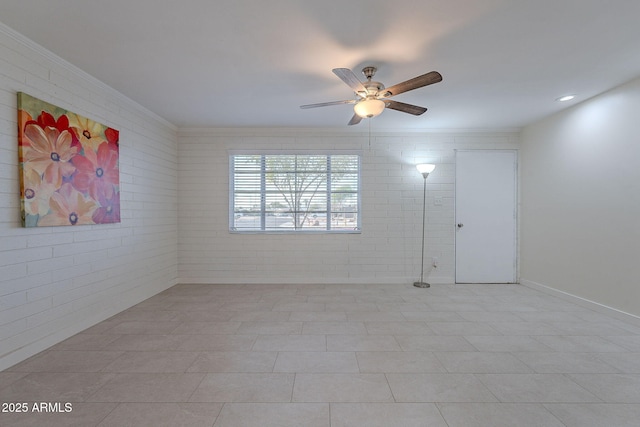 empty room with ornamental molding, ceiling fan, and brick wall