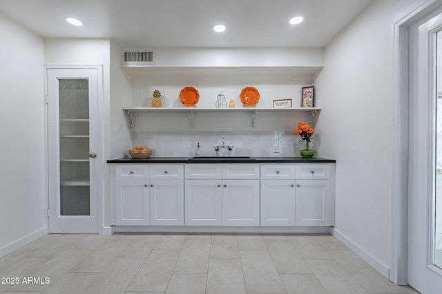 bar with white cabinetry, sink, and backsplash